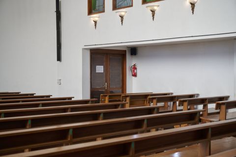 Perspektif interior kursi jemaat menghadap pintu ruang penyimpanan pelayan gereja